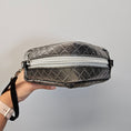 Load image into Gallery viewer, Quilted gray handbag with a zipper held by a hand against a light gray background