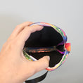 Load image into Gallery viewer, Hand holding a colorful fabric pouch against a gray background