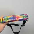 Load image into Gallery viewer, Colorful patterned strap with a black buckle held by a hand against a gray background