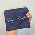 Load image into Gallery viewer, Navy blue pouch with white text held by a hand on a light gray background