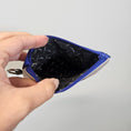 Load image into Gallery viewer, Hand holding a blue and gray zippered pouch with a patterned interior against a light gray background