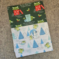 Load image into Gallery viewer, Two fabric swatches with Christmas-themed designs on a textured surface
