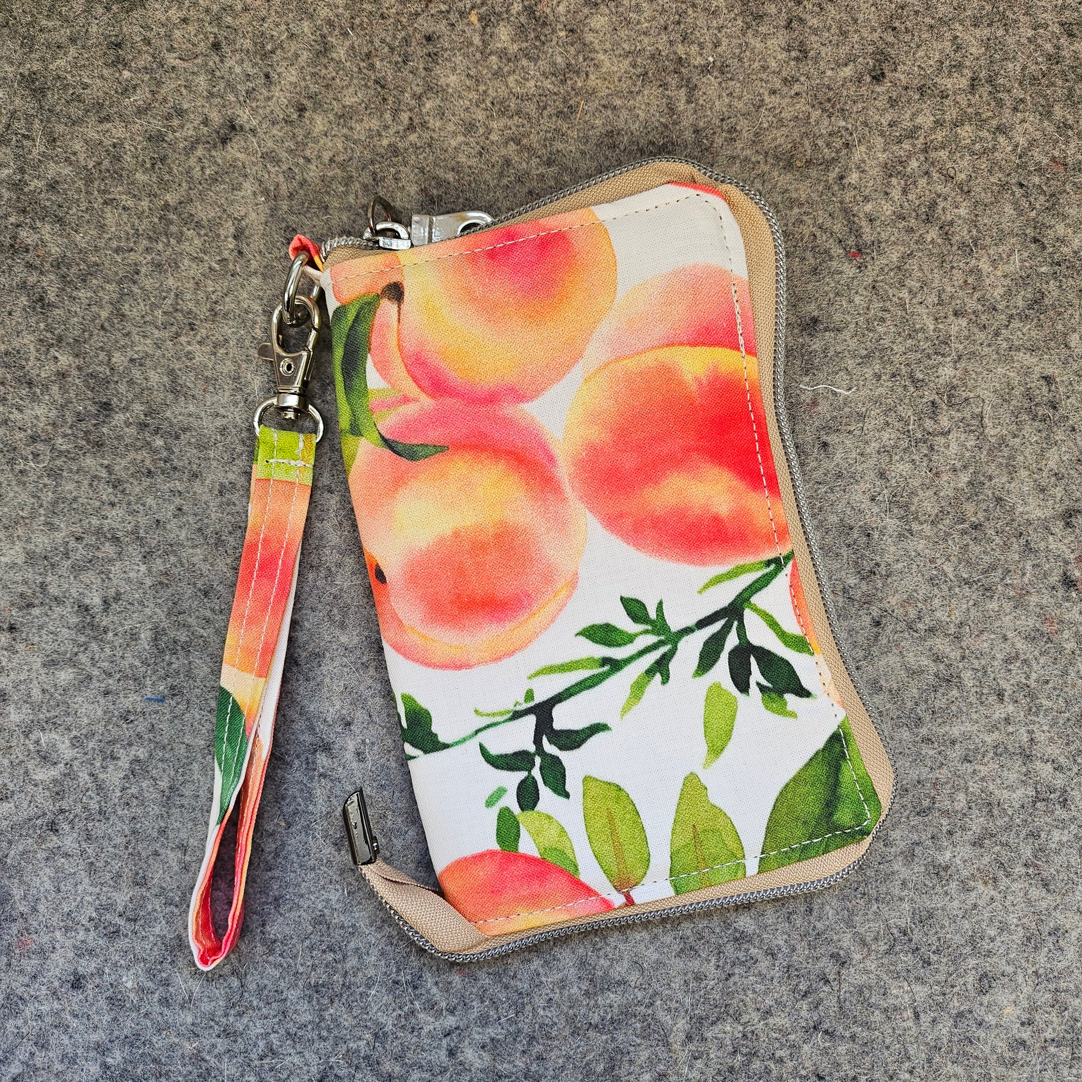 Wristlet with peach and leaf pattern on a textured surface