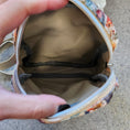 Load image into Gallery viewer, Floral-patterned makeup bag with a zipper, held open by hands on a neutral background