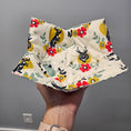 Load image into Gallery viewer, Hand holding a folded fabric with colorful floral and animal pattern against a gray background