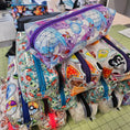 Load image into Gallery viewer, Colorful zippered pouches with various designs on a tiled surface