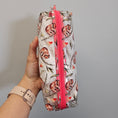 Load image into Gallery viewer, Floral-patterned pencil case with pink zipper held by a hand against a gray background