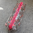 Load image into Gallery viewer, Clear pencil case with pink zipper and floral pattern on a gray surface