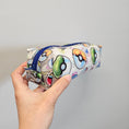 Load image into Gallery viewer, Pouch with colorful designs held by a hand against a gray background