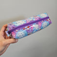 Load image into Gallery viewer, Pencil case with geometric pattern and purple zipper held by a hand against a gray background