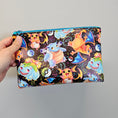 Load image into Gallery viewer, Pokemon vinyl zipper pouch held against a light gray background