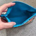 Load image into Gallery viewer, Blue pouch held open by a hand on a concrete surface