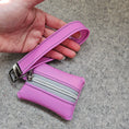 Load image into Gallery viewer, Pink wallet with a strap held by a hand on a gray surface