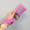 Load image into Gallery viewer, Pink leather bag with a strap held by a hand on a light gray background