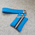 Load image into Gallery viewer, Blue wallet with a wrist strap on a gray background