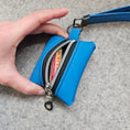 Load image into Gallery viewer, Blue wallet with a visible brand name held by a hand on a gray background