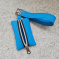 Load image into Gallery viewer, Blue pouch with a strap and zipper on a gray surface