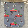 Load image into Gallery viewer, Gray fabric with red trucks and black and white characters on a textured surface