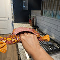 Load image into Gallery viewer, Person holding a floral-patterned bag in a kitchen setting
