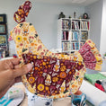 Load image into Gallery viewer, Handmade fabric chicken with floral patterns held in front of a fabric shelf.