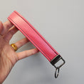 Load image into Gallery viewer, Pink leather keychain held by a hand against a gray background