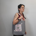 Load image into Gallery viewer, Person wearing the quilted heart tote with the main panel facing out.