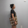 Load image into Gallery viewer, Person wearing the soft plaid flannel tote bag on their shoulder.