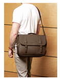 Load image into Gallery viewer, Person wearing a brown leather satchel bag against a wooden background