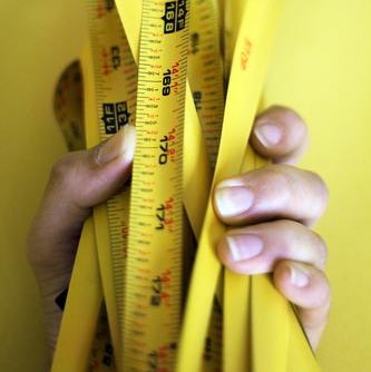 hand holding a bunch of yellow tape measures