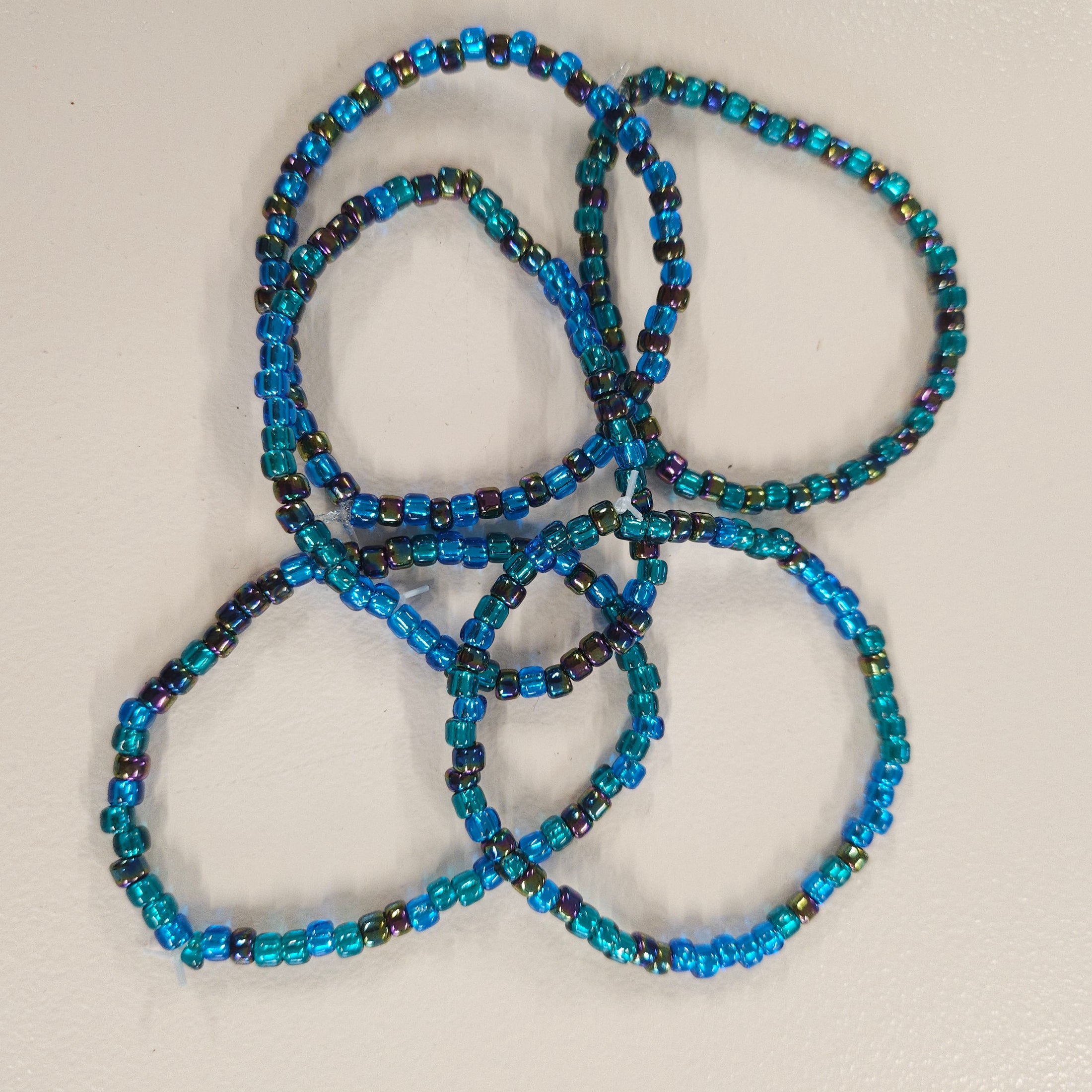 Blue, green and rainbow colored beaded bracelets.