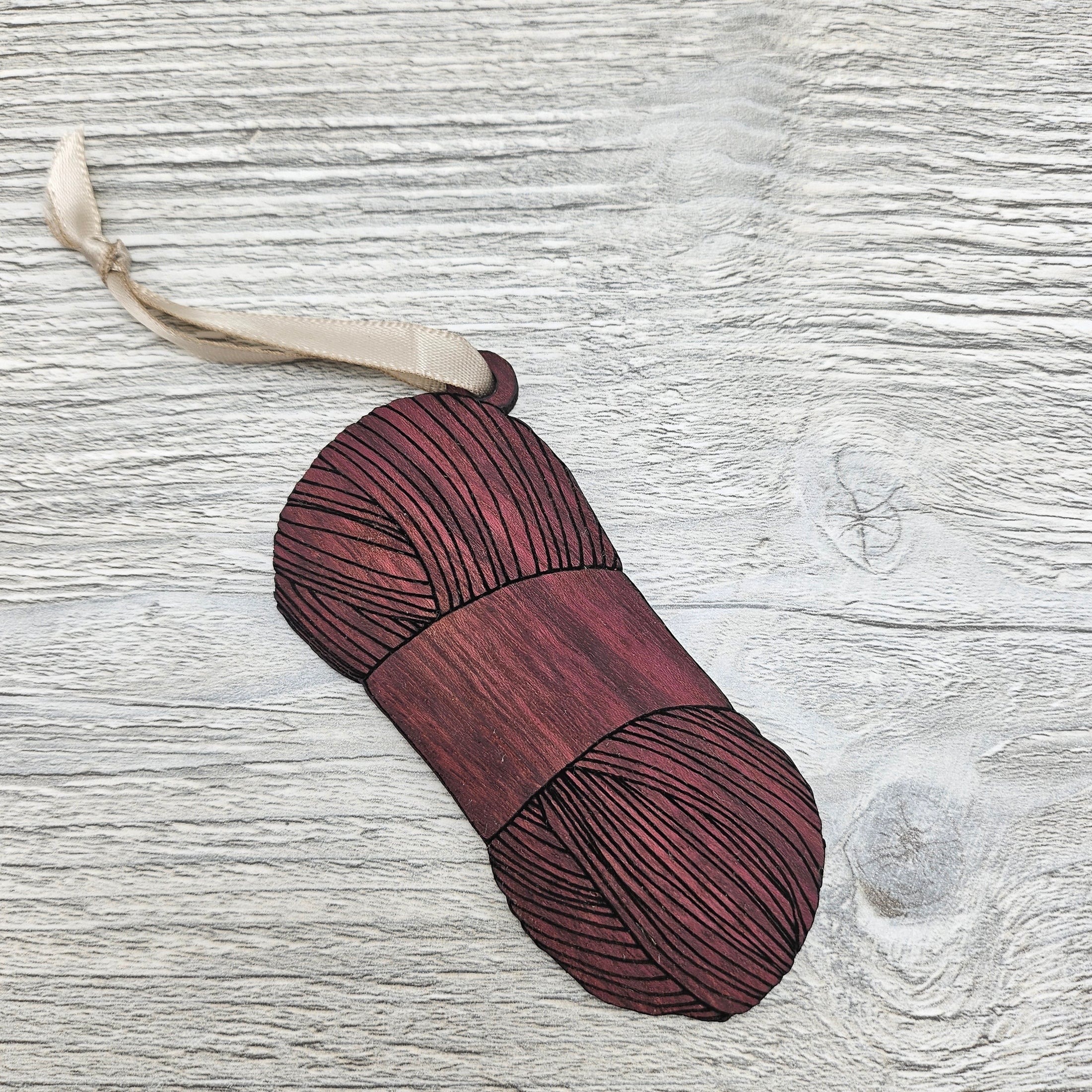 Yarn skein ornament laser cut from exotic purpleheart wood.