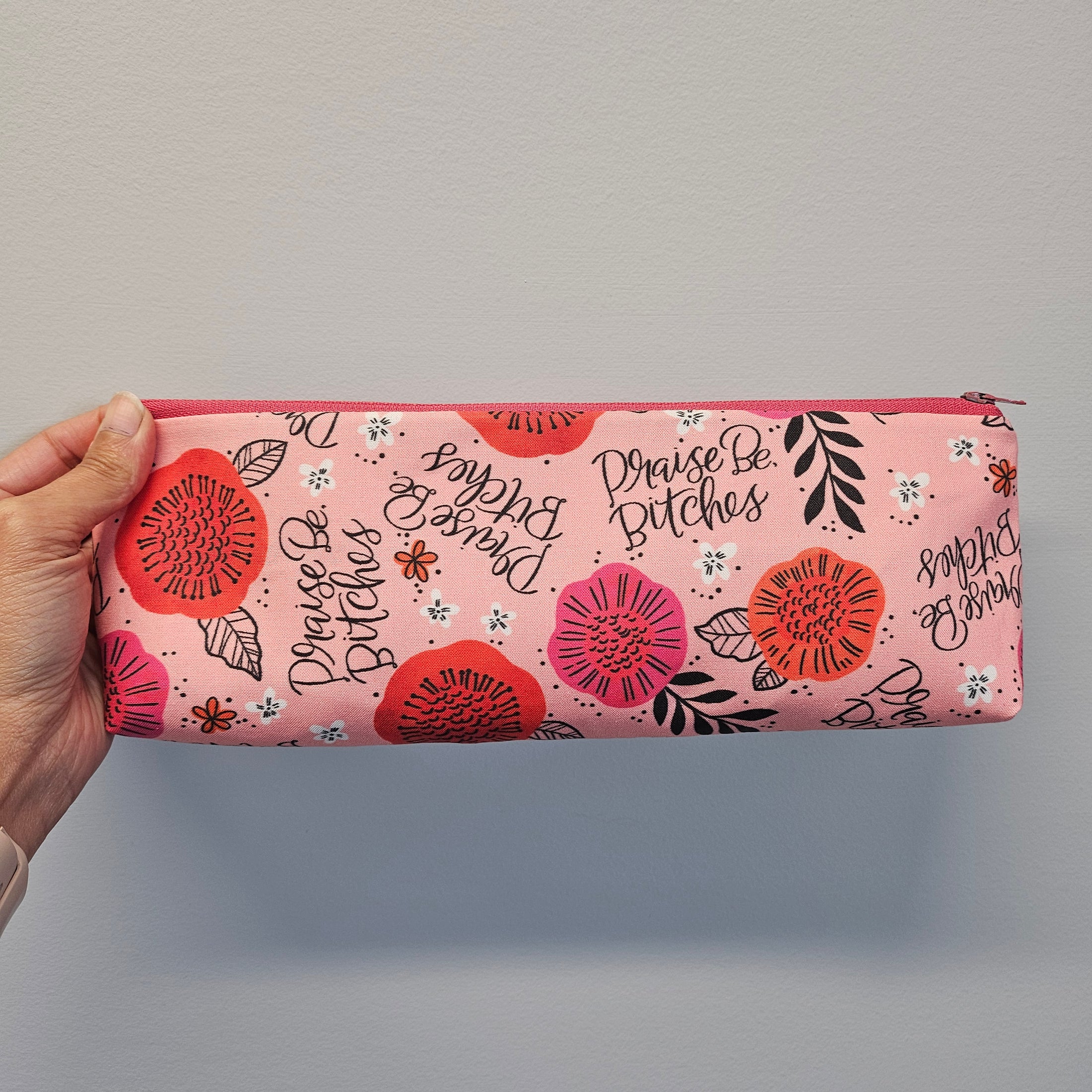 Praise be bitches zipper pouch on a light gray background.