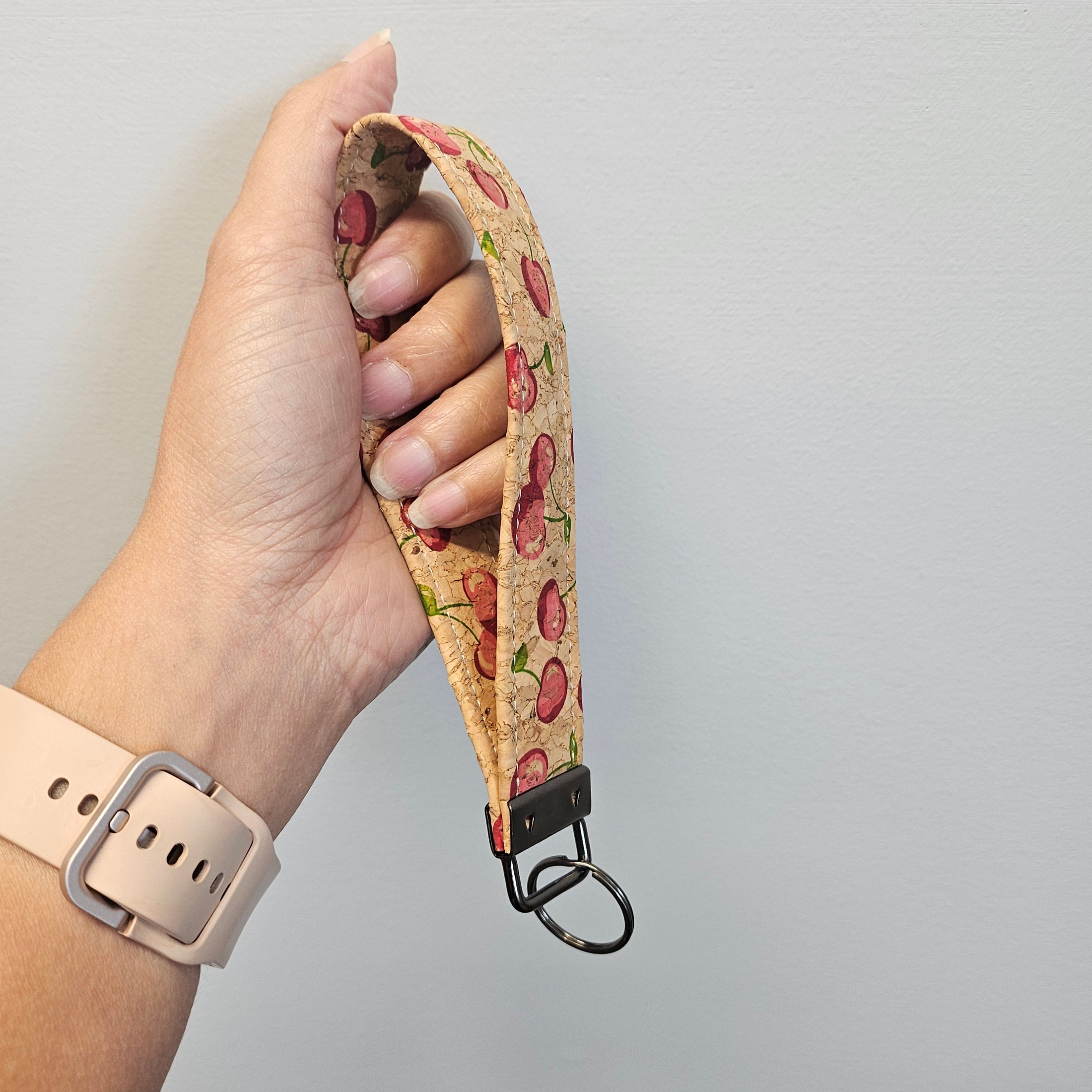 Hand holding a floral-patterned keychain strap against a plain background