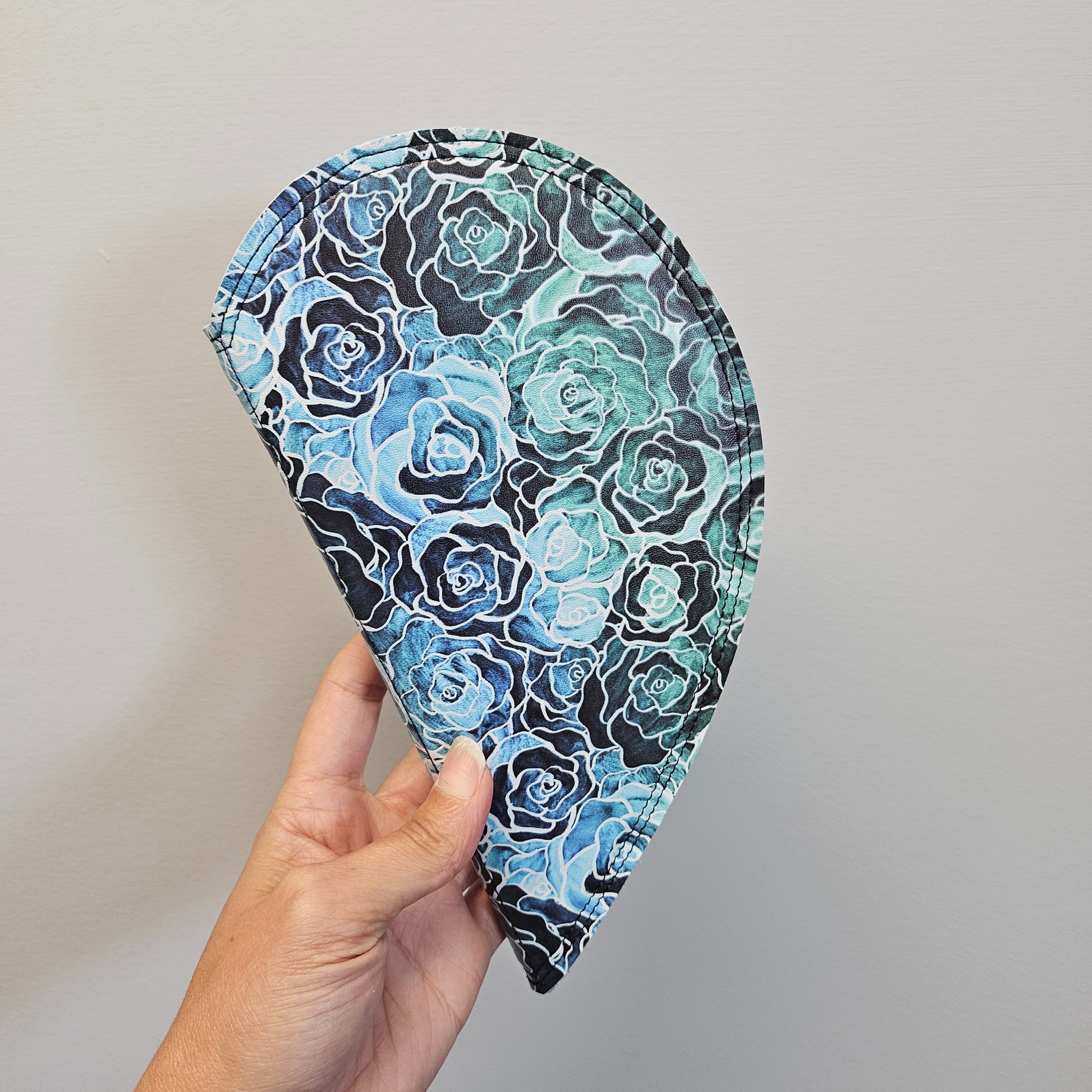 Hand holding a floral-patterned fabric item against a plain background