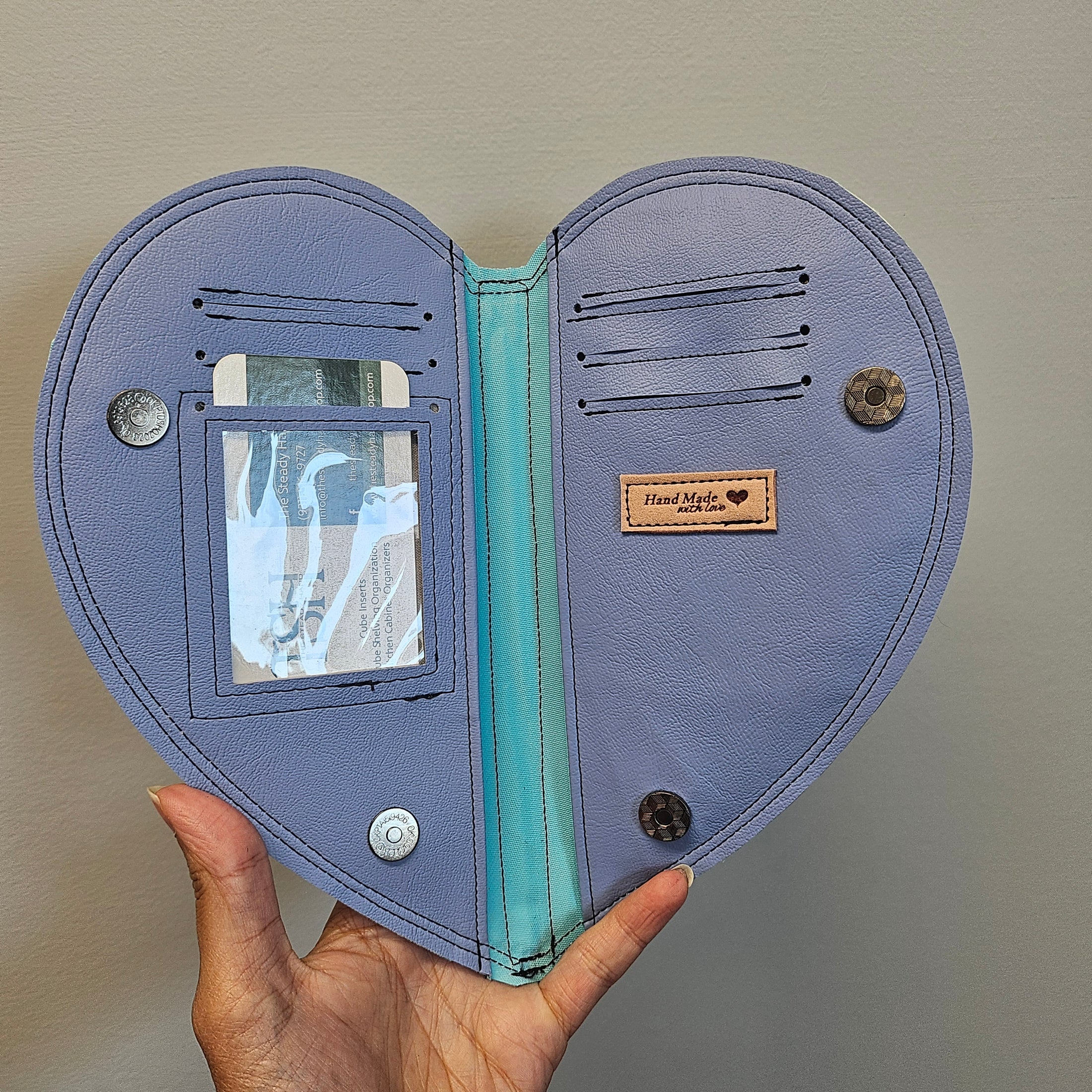 Open purple wallet with card slots and a visible brand label, held by a hand against a neutral background.
