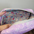 Load image into Gallery viewer, Purple pouch with colorful polka dot interior held by a hand against a neutral background
