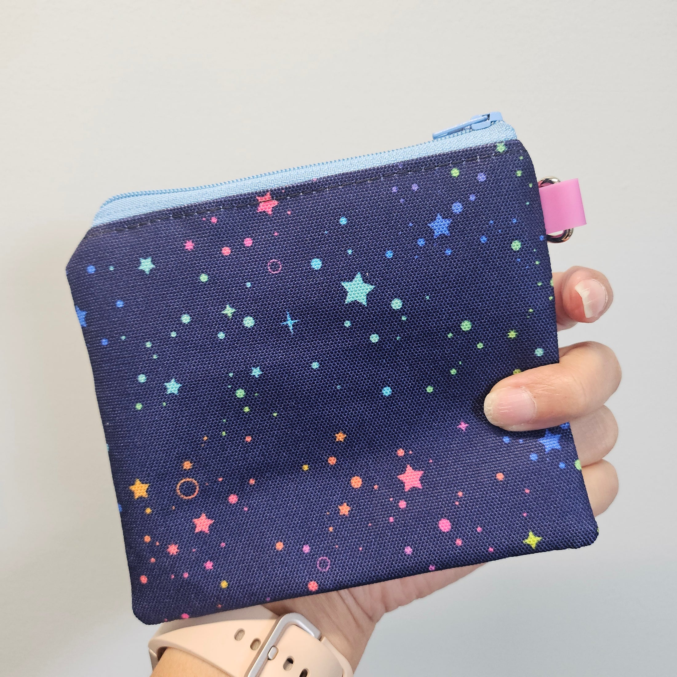 Small pouch with star pattern held by a hand against a neutral background