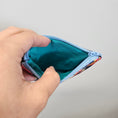 Load image into Gallery viewer, Hand holding a small blue and green zippered pouch against a plain background
