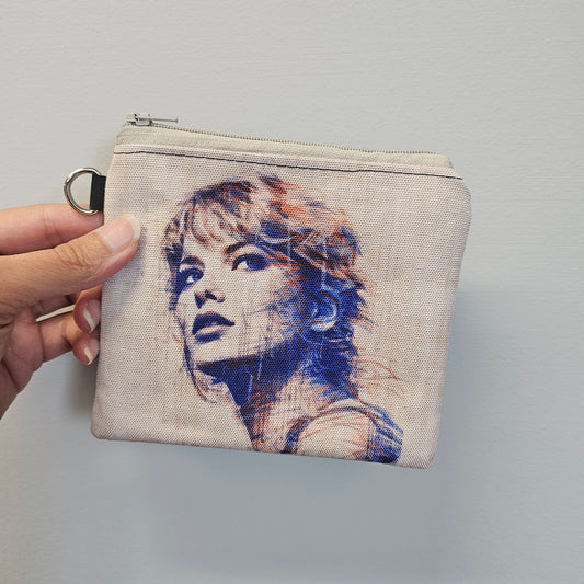 Hand holding a small pouch with a printed design on a gray background