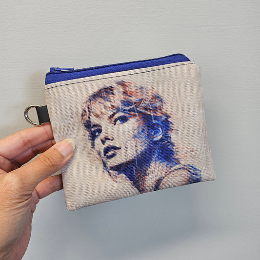Small pouch with a printed design held by a hand against a plain background