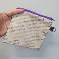 Load image into Gallery viewer, Small pouch with music note pattern held by a hand against a gray background
