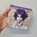 Load image into Gallery viewer, Hand holding a pouch with a graphic design of a face on a gray background
