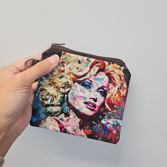 Colorful mosaic-style pouch held by a hand against a plain background