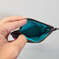 Load image into Gallery viewer, Small pouch with a zipper held open by a hand against a plain background
