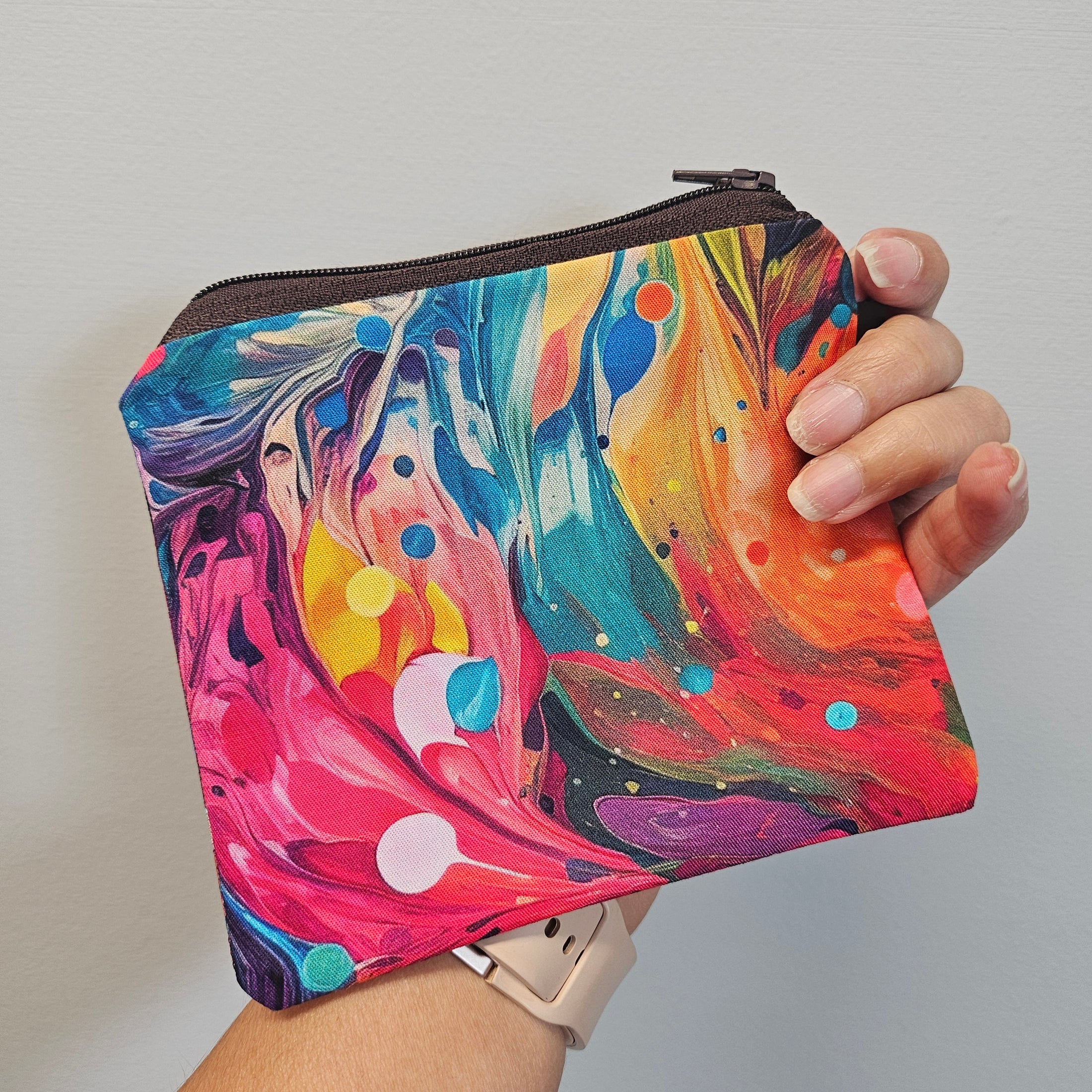 Colorful marbled pouch held by a hand against a neutral background