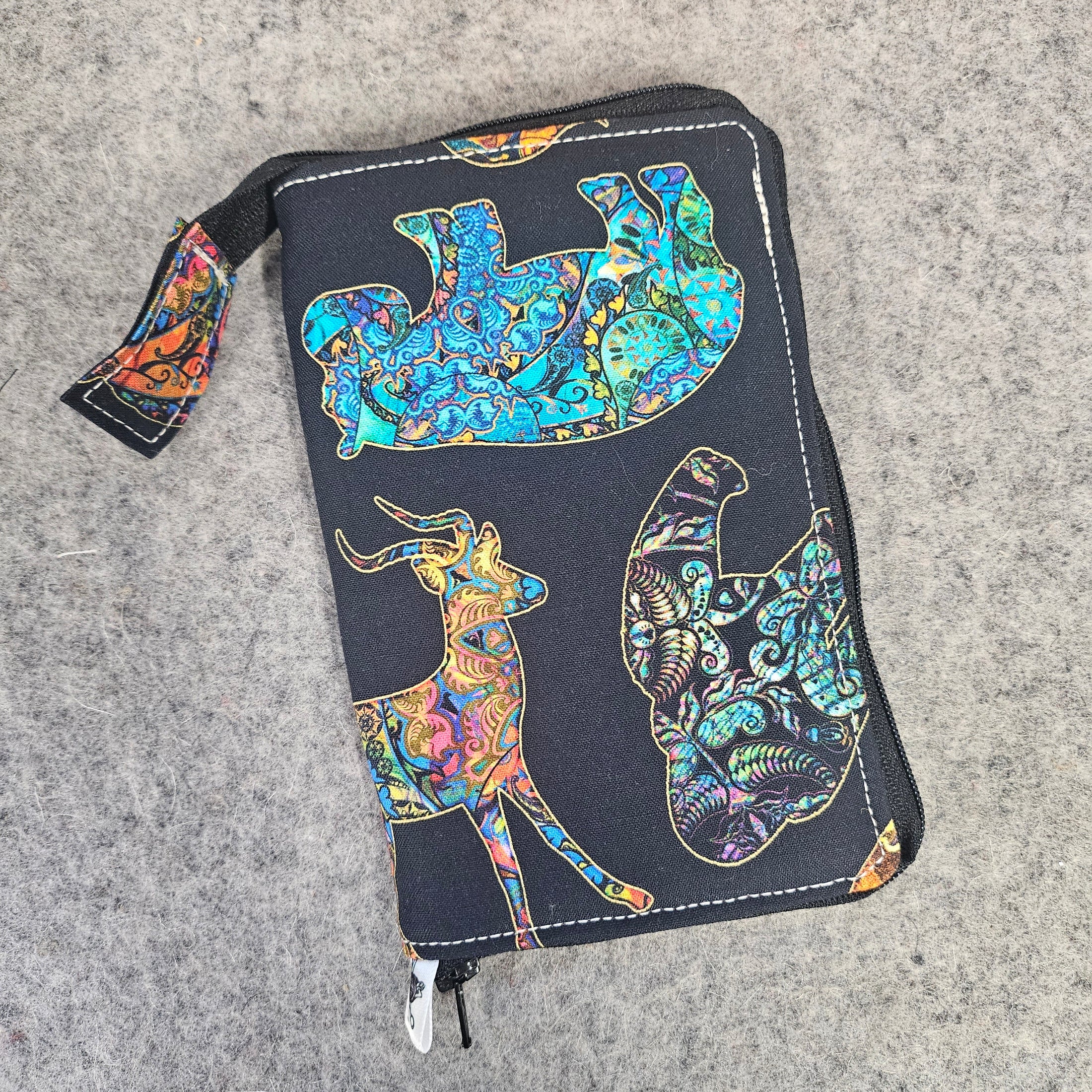 Colorful animal design on a black pouch against a gray background