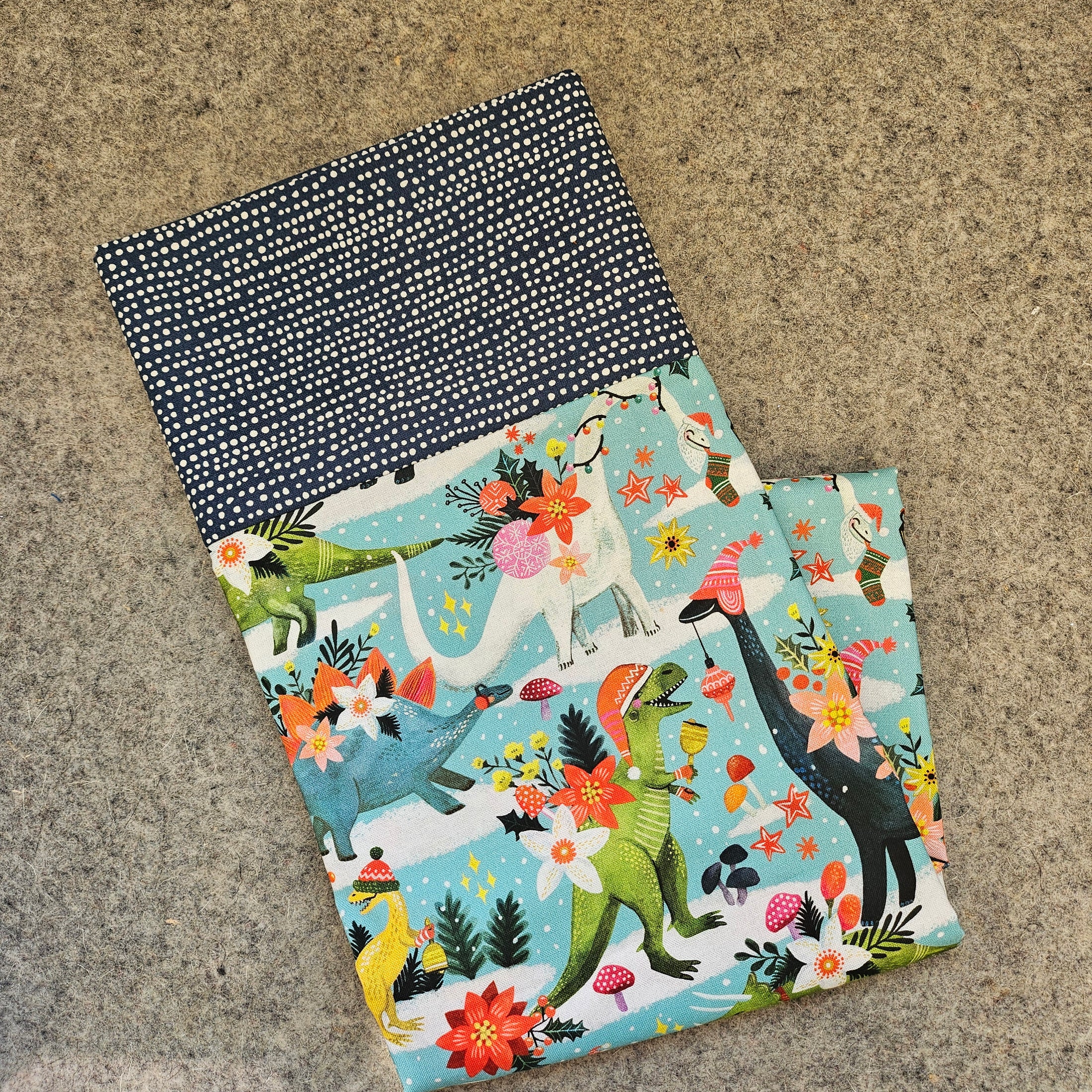 Folded pillowcase featuring dinosaurs celebrating Christmas.