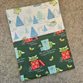 Load image into Gallery viewer, Two fabric swatches with Christmas-themed patterns on a textured surface.
