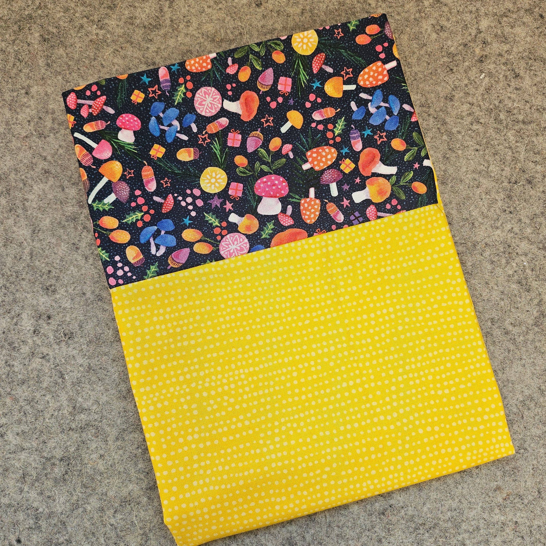 Two fabric swatches, one with a colorful mushroom pattern and the other with a yellow polka dot pattern, on a textured surface.