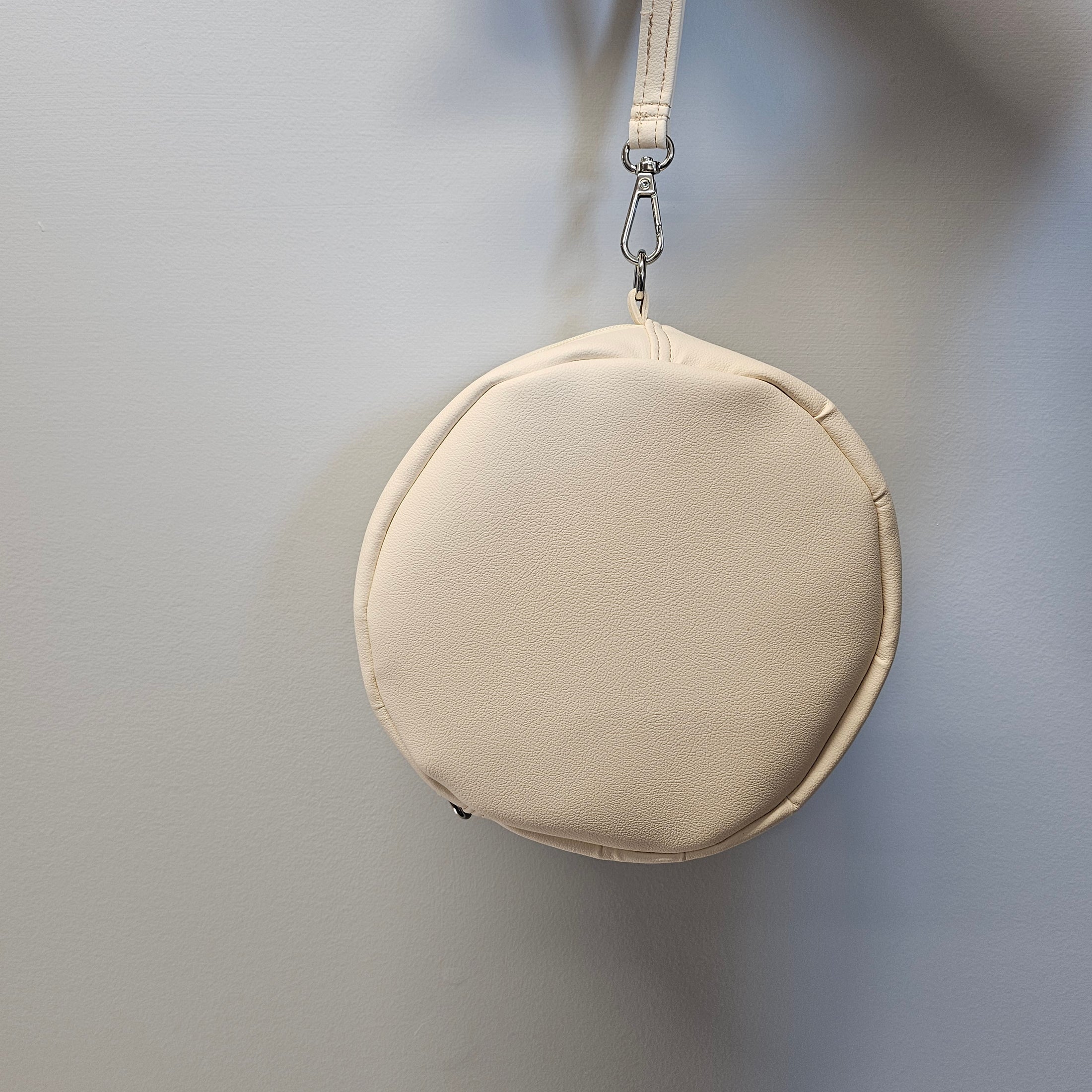 Beige round handbag with a strap on a light gray background